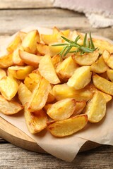 Tasty baked potatoes with rosemary on wooden table, closeup