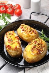 Tasty stuffed baked potatoes in baking dish on grey table, closeup