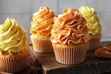 Delicious cupcakes with colorful cream and autumn decor on table, closeup