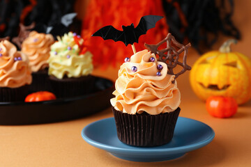Delicious cupcake with chocolate web, bat topper and sprinkles on orange table against color background, closeup with space for text. Halloween celebration