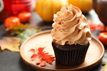 Delicious cupcake and autumn leaves on grey table, closeup with space for text