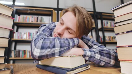 Student sleeping on books while studying in a library during the afternoon hours, surrounded by shelves full of colorful books - Powered by Adobe