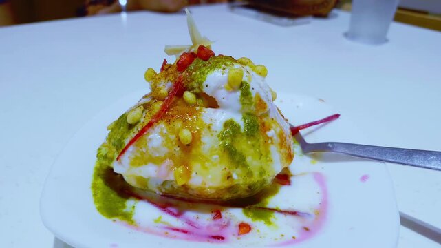 Closeup reveals raj kachori chaat with curd, toppings, and sauces on a plate, focusing on intricate details.