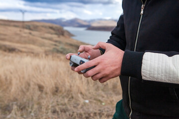 Man holding a remote control of a drone in the field. Close-up.