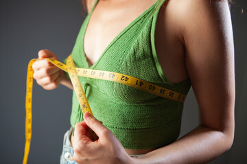 Young woman measuring her waist with a tape measure, close-up