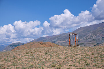 Religious wooden construction in Altai mountains. In background Kurai mountain range under blue sky and clouds.