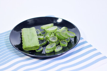 Sliced Aloe Vera in a Black Plate on a Placemat with a White Background