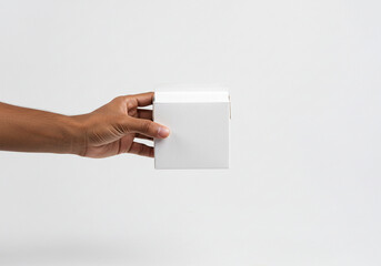 Hand presenting a clean white product box for modern packaging design and branding mockups, offering a blank canvas for creative ideas.