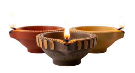 Three lit clay diyas isolated on transparent background, traditional indian lamps for diwali festival