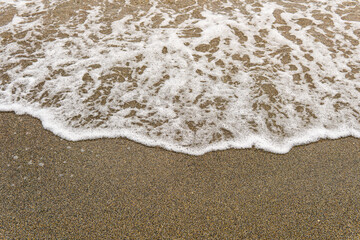 White sea foam washing onto wet sand.