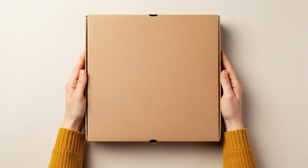 Hands holding blank cardboard pizza box for branding mockup on neutral background