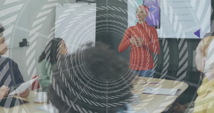 Woman introducing agenda initiating gesturing at slide in project update, colleagues taking notes