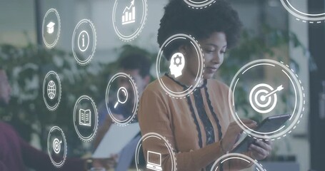 Woman tapping tablet at office table activating spinning tech bar chart icons for team review - Powered by Adobe