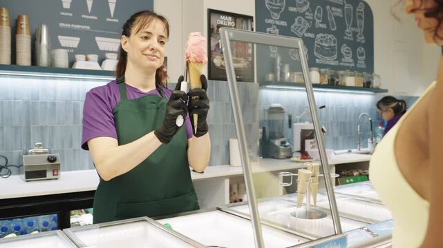 Ice cream parlor employee serving strawberry cone