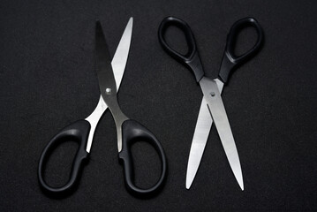 Two scissors on a black background. Stationery scissors.