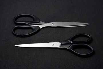 Two scissors on a black background. Stationery scissors.