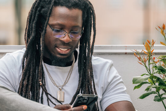 young african man with dreadlocks and mobile phone on the terrace
