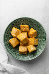 Overhead view of fried tofu in a green bowl, top view of pan fried soya bean tofu cubes