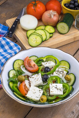 Fuente de ensalada griega e ingredientes en una tabla de cocina
