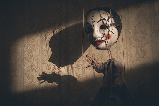 Cracked marionette puppet casting shadow in dramatic light