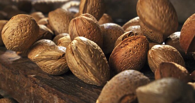 Slow Motion of Macro Falling Almonds In Shell Bouncing on Wooden Rustic Table Surface with Natural Light and Shadows at 1000 fps.
