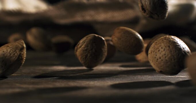 Slow Motion of Macro Falling Almonds In Shell Bouncing on Wooden Rustic Table Surface with Natural Light and Shadows at 1000 fps.