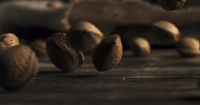 Slow Motion of Macro Falling Almonds In Shell Bouncing on Wooden Rustic Table Surface with Natural Light and Shadows at 1000 fps.