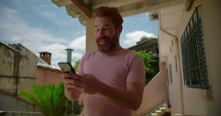 Bearded man outdoors looking at smartphone with worried expression, scratching neck, reacting to...