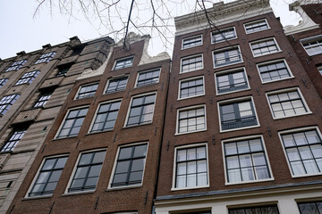 View of historic brick buildings with large windows in Amsterdam under a cloudy sky