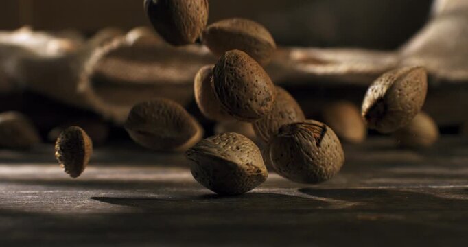 Slow Motion of Macro Falling Almonds In Shell Bouncing on Wooden Rustic Table Surface with Natural Light and Shadows at 1000 fps.