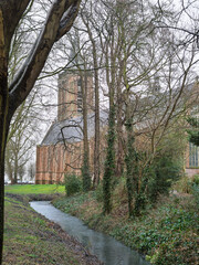 Vertical photo of Grote Kerk (Monnickendam, Netherlands) among bare trees in winter