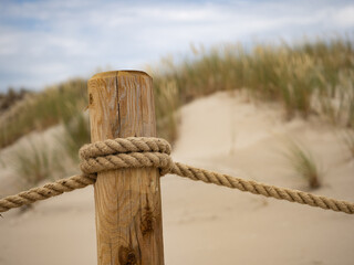 Weathered Wooden Post With Rope Along a Sandy Dune Path Under a Clear Sky