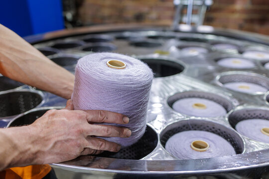 Worker loading yarn cone into dyeing machine basket in textile factory