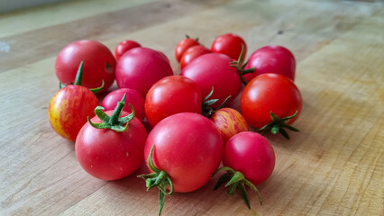 Vibrant collection of freshly picked red cherry and heirloom tomatoes with green stems, resting on...