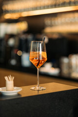Aperol Spritz Cocktail im Weinglas an eleganter Bar mit Zitrusfrüchten