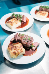 Tranchiertes Rinderfilet auf Teller mit Kartoffelgratin und Sauce
