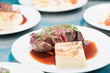 Tranchiertes Rinderfilet auf Teller mit Kartoffelgratin und Sauce