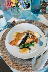 Knuspriges Hähnchenbrustfilet mit Kartoffeln, Gemüse und Sauce, elegant serviert auf gedecktem Tisch