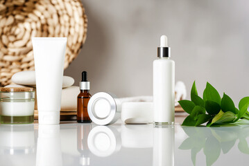 Mockups of jars for cosmetic skin care products on a light background with reflection. Moisturizer, lotion, facial serum, cream, tonic or micellar water. Eco-cosmetics
