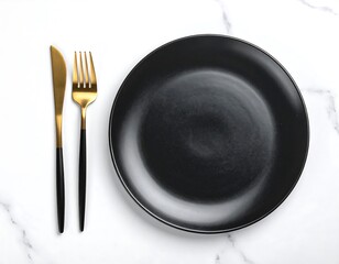 Black plate with gold cutlery on white marble