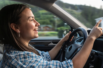 Young woman enjoys driving car. Happy journey on the move