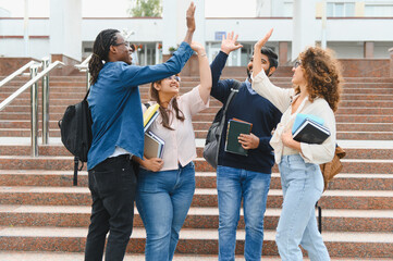 Fototapeta premium Diverse university students celebrating academic success high fiving outdoors