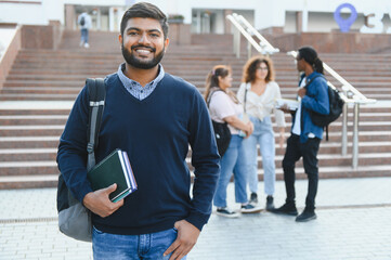 Smiling indian student holding books on campus