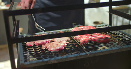 Close-up of sizzling steaks and sausages on barbecue grill, meat cooking outdoors during casual backyard family gathering