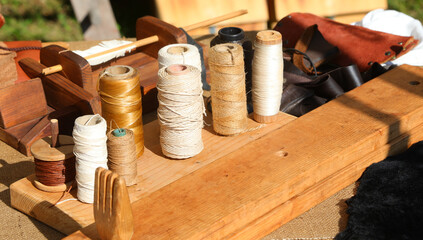 spools or balls of sewing thread on a tailor work bench with medieval setting