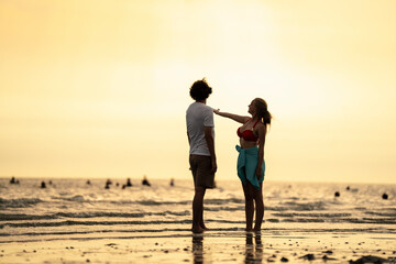 Fototapeta premium Happy young couple enjoying playful piggyback ride at the beach during sunset. Perfect for concepts like romance, summer vacation, freedom, fun, and relationship lifestyle imagery.