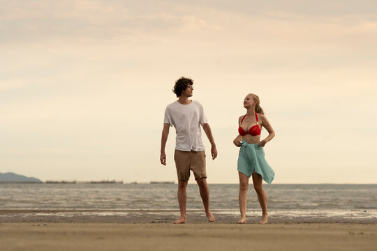 Happy young couple enjoying playful piggyback ride at the beach during sunset. Perfect for concepts like romance, summer vacation, freedom, fun, and relationship lifestyle imagery.