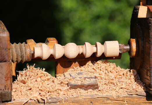 Piece of wood on a lathe and wood shavings from the process in a carpentry workshop