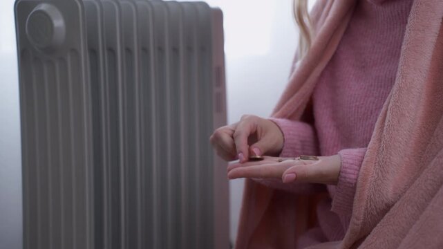 Freezing woman wrapped in blanket counting last of her money for heating expenses, symbolizing energy crisis and high cost of electricity during cold winter season
