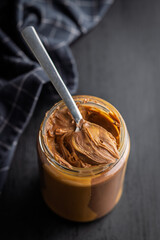 Two-tone nut chocolate spread in jar on black table.